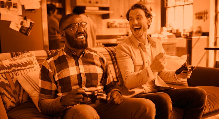 Two adult male friends sitting in their living room playing video games and having a great time