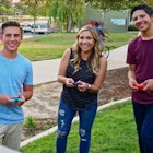 A woman and her two sons playing Mario Tennis outside