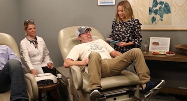 Andy Lassner sitting with his legs spread on a gynecology chair Kristen Bell’s "Momsplaining" TV sho...