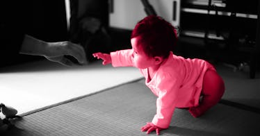 pink photo edit of a baby starting to crawl - against a black and white background.