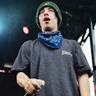 Rapper Lil Xan in a grey shirt, green beanie and blue scarf performing on stage