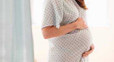 Pregnant woman in scrub holding her belly