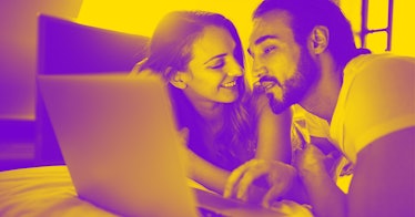 A man and woman laying on a bed, in front of a laptop, looking amused and happy while searching for ...