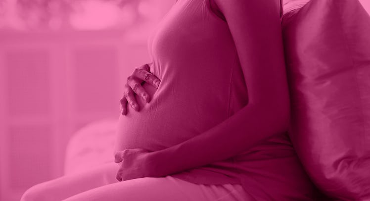 A pregnant girl sitting on a couch and holding her belly