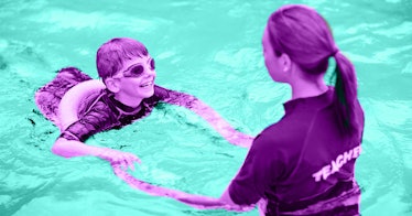 A kid wearing a floatie and goggles at a swimming lesson with an instructor