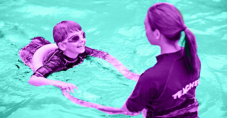 A kid wearing a floatie and goggles at a swimming lesson with an instructor