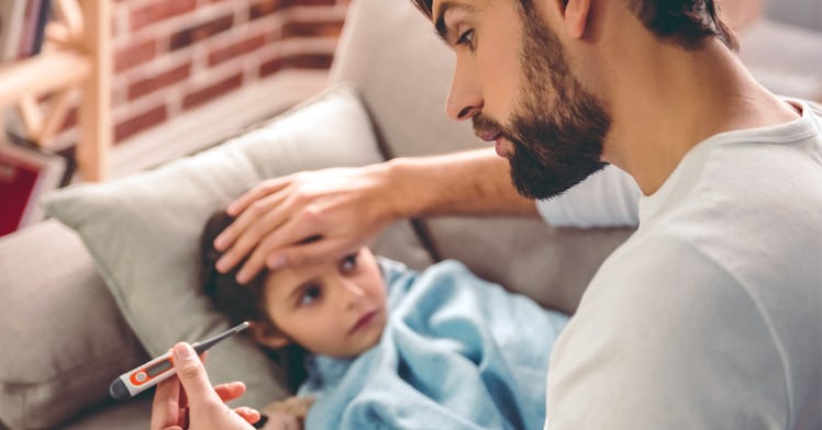 A father takes his son's temperature.