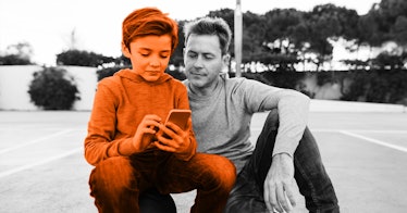 A dad with his son, monitoring the son's activity on his phone in order to prevent child abduction