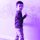 3-year-old boy drawing with color pencils on a white wall