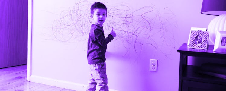 3-year-old boy drawing with color pencils on a white wall