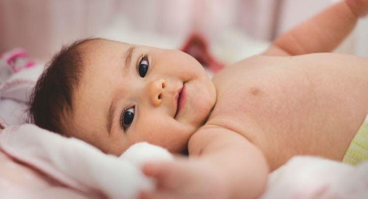 A happy baby lying on its back slightly turned to the left side