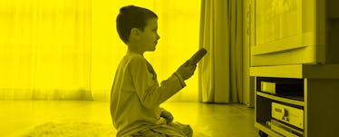 A kid in sitting in front of the TV and holding a remote during screen time