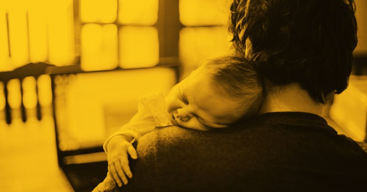 Father with baby on shoulder looking at online services on laptop