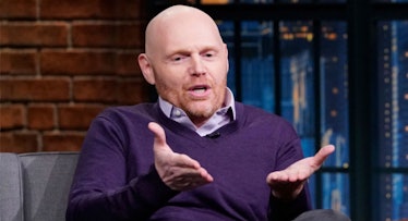 Bill Burr gesticulating with his hands while wearing a purple sweater on a talk show