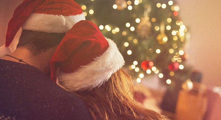 Married couple sitting hugged next to a Christmas tree