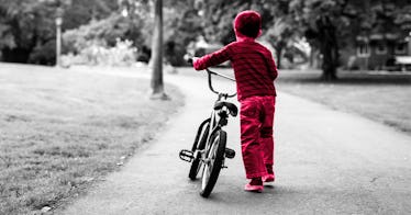 grey edit of a kids walking his bike on a lonely path