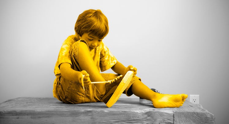 A young child ties his shoes