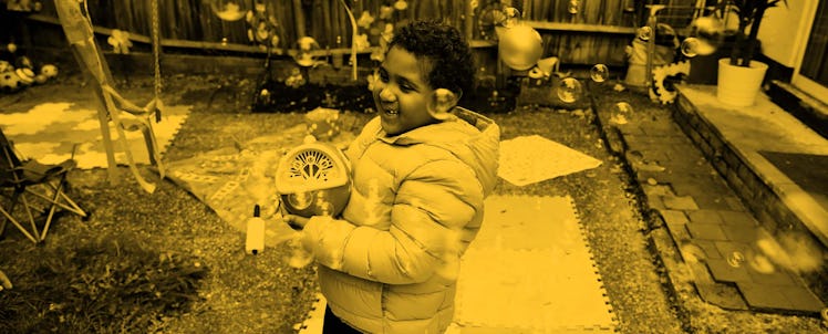 yellow edit of a child outside making bubbles with a machine