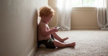 A child sitting on the floor, using a tablet.