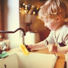 A young boy washing dishes - coronavirus chores for kids