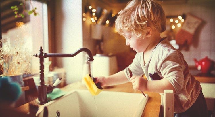 A young boy washing dishes