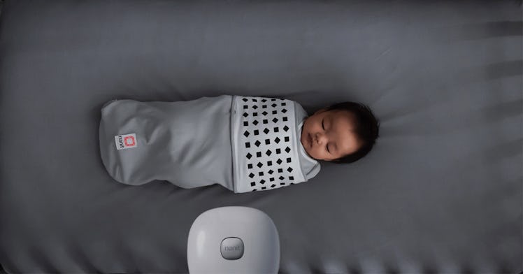 A small baby sleeping while wearing grey Nanit breathing wear