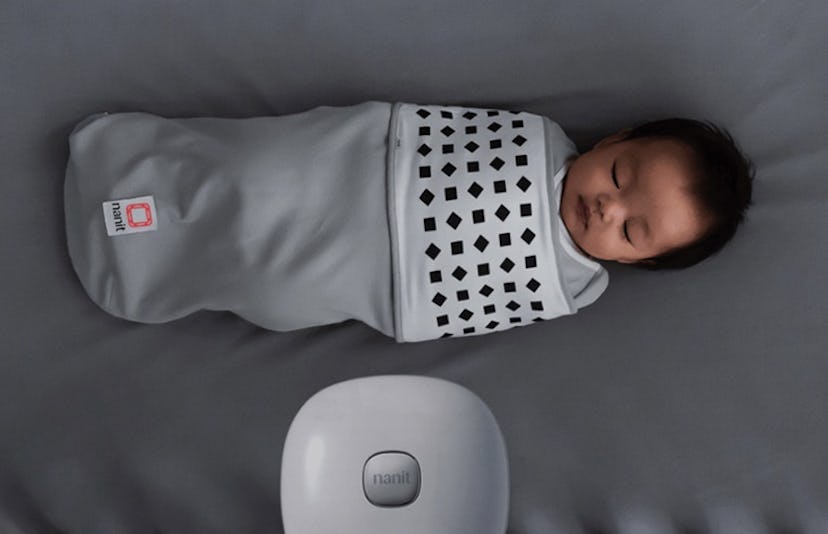 A small baby sleeping while wearing grey Nanit breathing wear