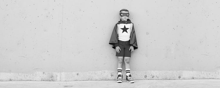 A kid in a black and white photo dressed as a superhero, wearing a mask and a star on his chest
