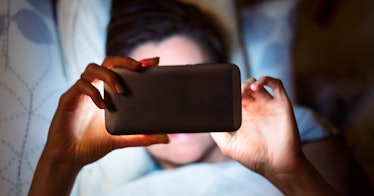 woman in bed is phubbing her partner by concentrating on her smartphone