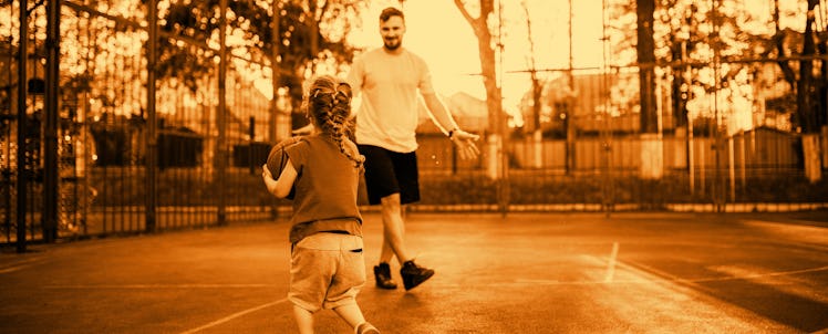 A dad playing basketball with his daughter