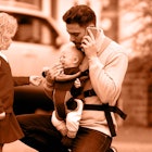 A father talking on a phone while standing on a street with his two kids