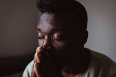 Man with eyes closed and hands in prayer.