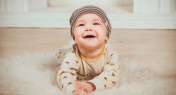 A baby lying on a floor carpet and laughing