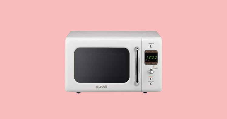 The Daewoo KOR-7LREW Retro Countertop Microwave Oven in white on a pink background