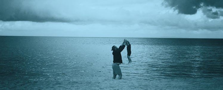 A man playing with his toddler in the ocean 