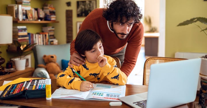 A dad helps his hardworking child do homework.