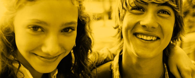 A young couple with their arms around each other smiling and looking at the camera