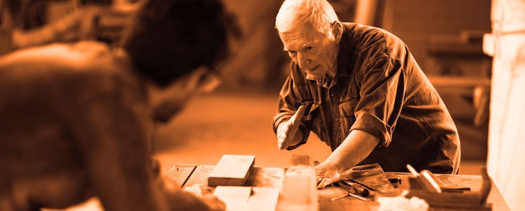 A middle-aged man woodworking with his dad