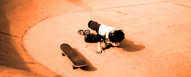 A little boy falling of a skateboard at a skate park