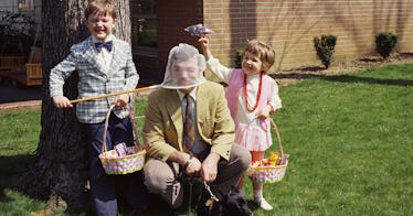 two kids holding easter baskets with dad in yellow suit crouching beside them telling easter jokes