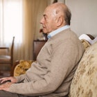 An aging man sitting alone on a couch