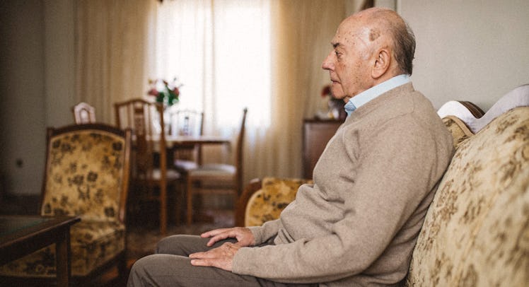 An aging man sitting alone on a couch