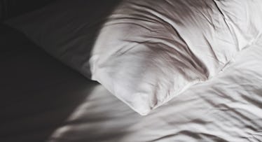 A crumpled pillow which is half lit and half in shadow