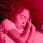 A little curly-haired girl sleeping on her side with a pink color filter
