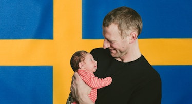 A man holding his newborn baby in front of the Swedish flag