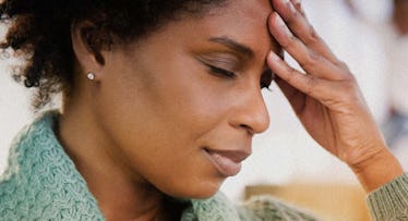 mother in green sweater closing her eyes and pressing her hand to her forehead