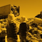 Two kids looking at garbage trucks at the dump