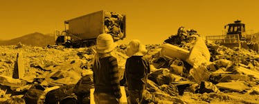 Two kids looking at garbage trucks at the dump