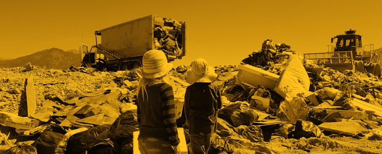 Two kids looking at garbage trucks at the dump