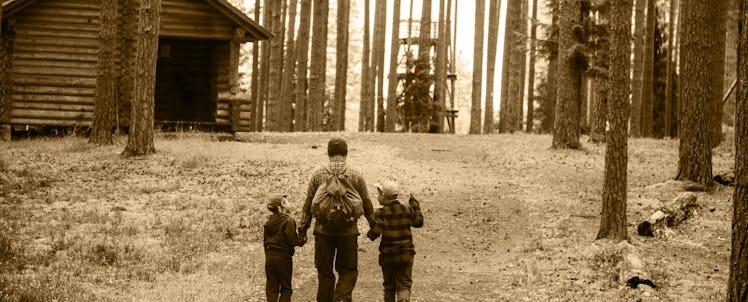 A father and two children walking through the woods on their way to a campsite